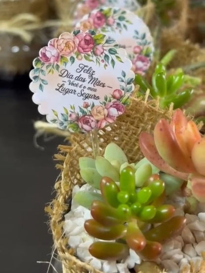 Foto real de perto: tag personalizada floral no cachepô de juta com suculenta e pedrinhas brancas